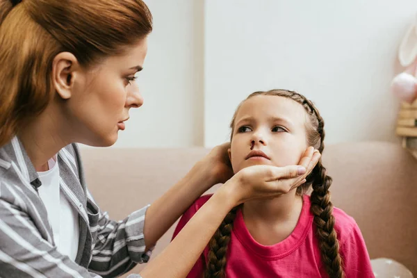 Worried mother looking at sad daughter with nasal bleeding — Stock Photo
