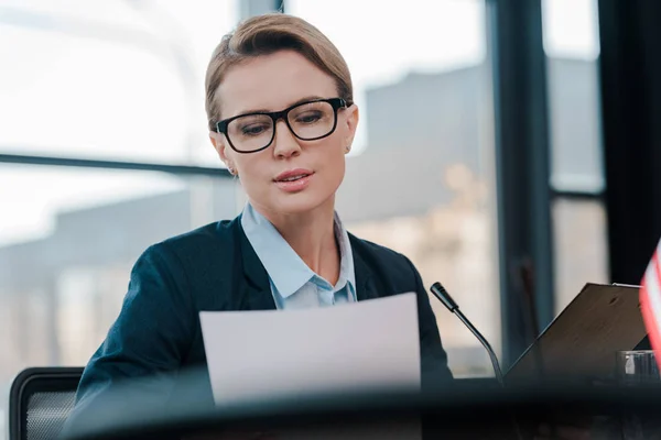 Enfoque selectivo de atractivo diplomático en gafas mirando el documento - foto de stock