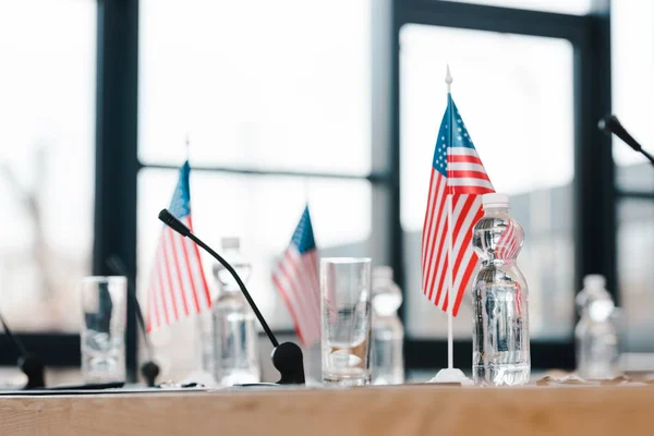 Selective focus of american flags near glasses and bottles with water on table — Stock Photo