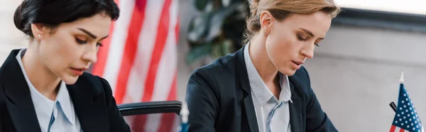 Panoramic shot of attractive businesswoman near american flags — Stock Photo