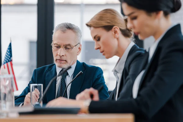 Selective focus of bearded businessman near attractive diplomats — Stock Photo