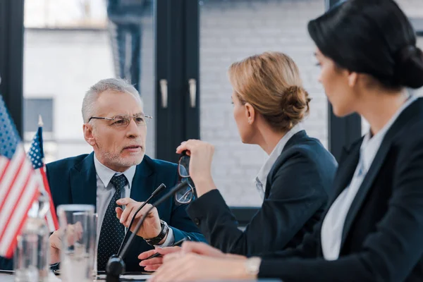 Selective focus of bearded businessman looking at attractive diplomats — Stock Photo