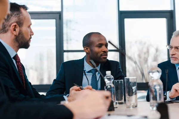 Selective focus of handsome multicultural diplomats near microphones — Stock Photo