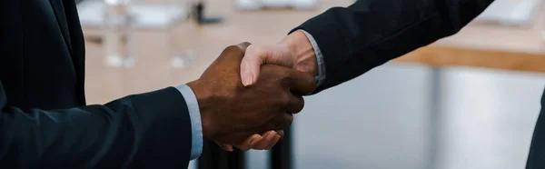 Tiro panorâmico de empresária apertando as mãos com o empresário afro-americano — Fotografia de Stock