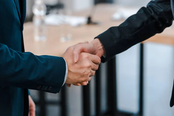 Vista recortada de la mujer de negocios estrechando la mano con el hombre de negocios - foto de stock