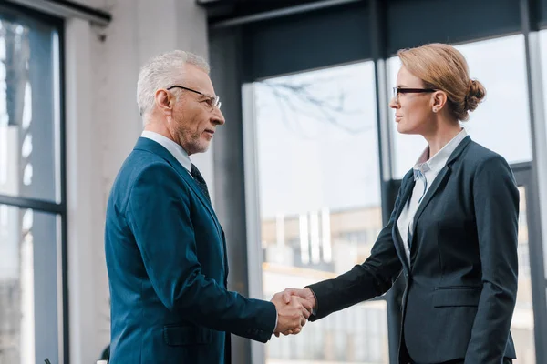 Side view of businesswoman shaking hands with businessman in glasses — Stock Photo