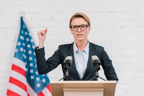 Emotional speaker in glasses gesturing while talking near microphones — Stock Photo