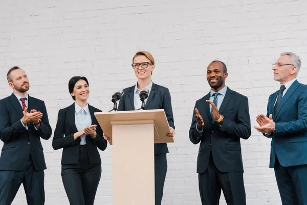 Heureux hommes d'affaires multiculturels et femme d'affaires applaudissant à l'orateur attrayant — Photo de stock