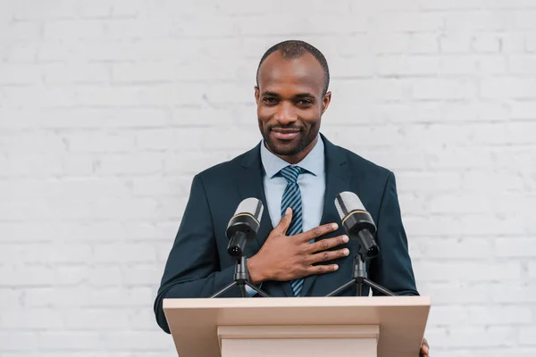 Cheerful african american speaker smiling near microphones — Stock Photo