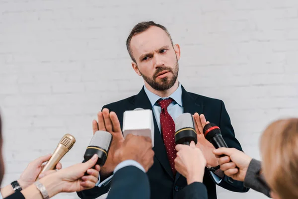 Перекручений погляд журналістів, які тримають мікрофони біля бородатого дипломата, не показує жодних жестів. — стокове фото