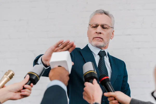 Cropped view of journalists holding microphones near diplomat showing no gesture — Stock Photo