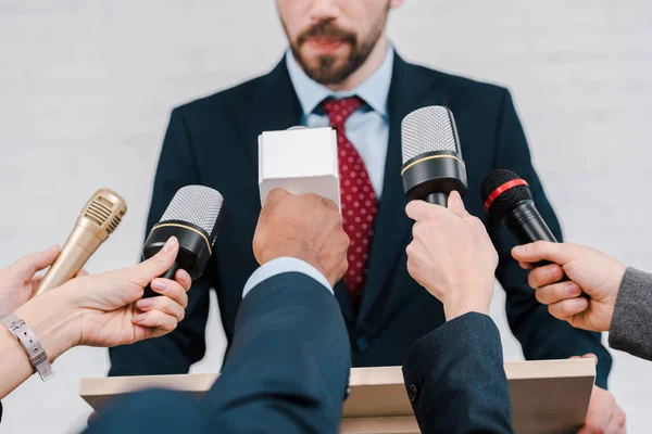 Cropped view of journalists holding microphones near diplomat — Stock Photo