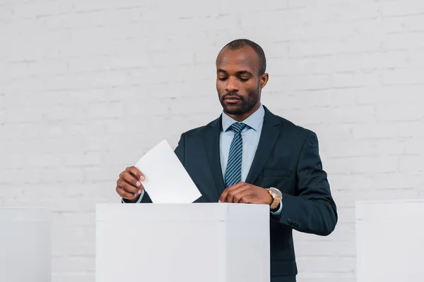 Handsome african american businessman voting near brick wall — Stock Photo