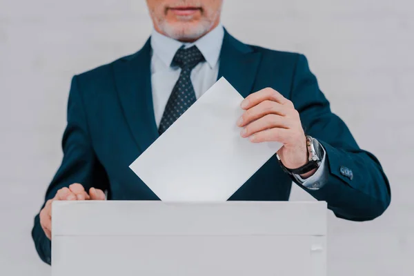 Cropped view of bearded businessman voting near brick wall — Stock Photo