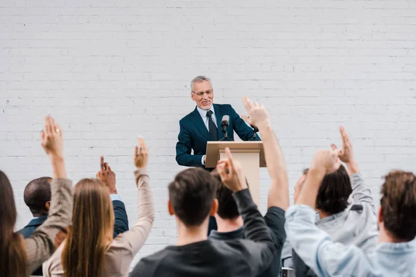 Back view of journalists with raised hands near happy bearded speaker — Stock Photo
