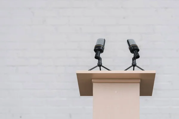 Support en bois avec microphones près du mur de briques blanches — Photo de stock