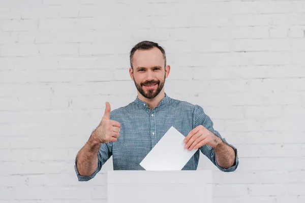 Cheerful voter showing thumb up while holding blank ballot — Stock Photo