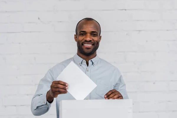 Votante afro-americano feliz colocando cédula em branco na caixa de votação — Fotografia de Stock