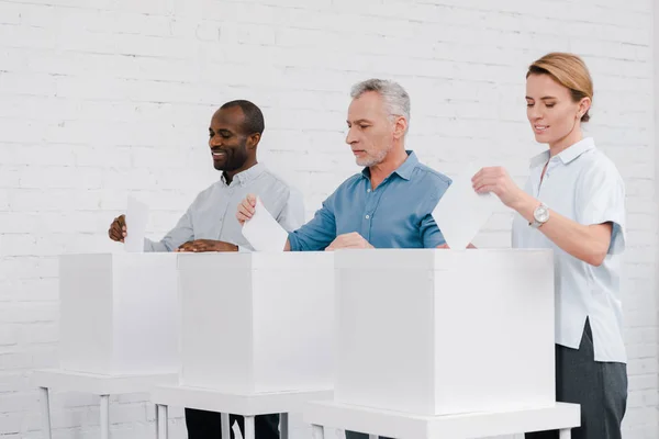 Cidadãos multiculturais alegres votando enquanto estão perto de caixas — Fotografia de Stock