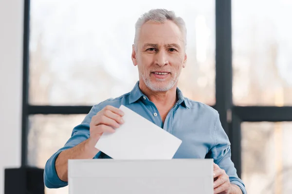 Glücklicher bärtiger Bürger, der wählt und in die Kamera schaut — Stockfoto