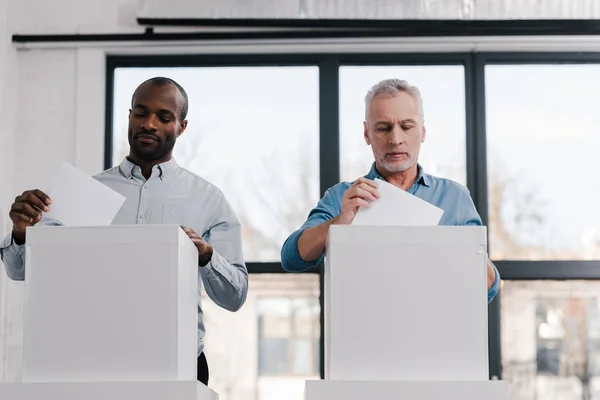 Multicultural citizens putting ballots into voting boxes — Stock Photo