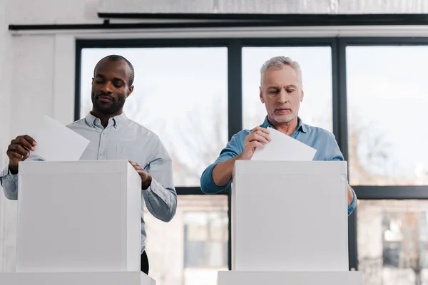 Citoyens multiculturels qui mettent des bulletins de vote dans les urnes — Photo de stock