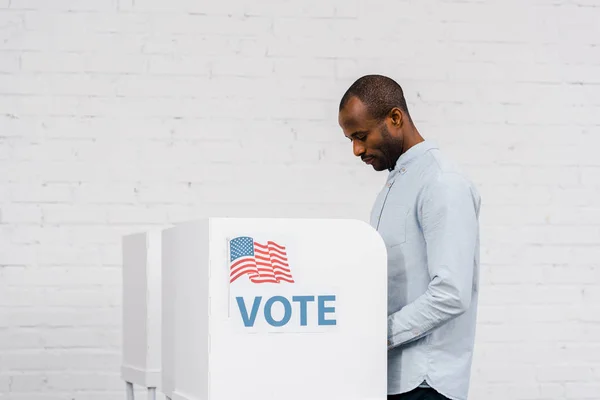 African american citizen voting near stand with vote lettering — Stock Photo