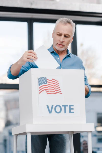 Bearded man voting and putting ballot in box with vote lettering — Stock Photo