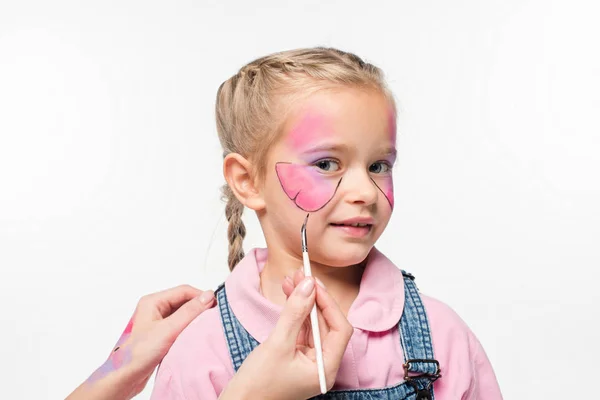 Vista parcial de artista pintura mariposa en la cara de niño adorable aislado en blanco - foto de stock