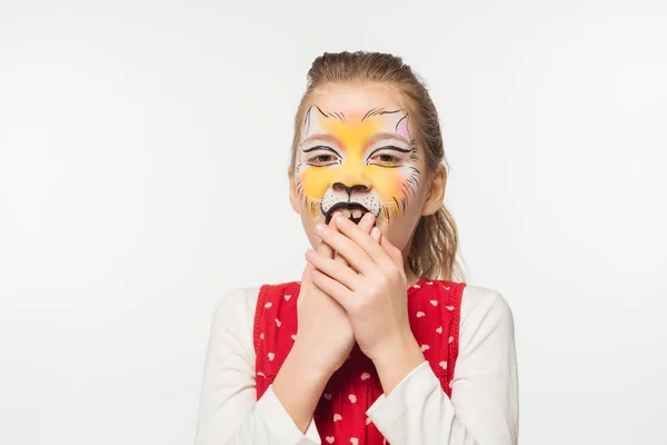 Excited child with tiger muzzle painting on face covering eyes with hands isolated on white — Stock Photo