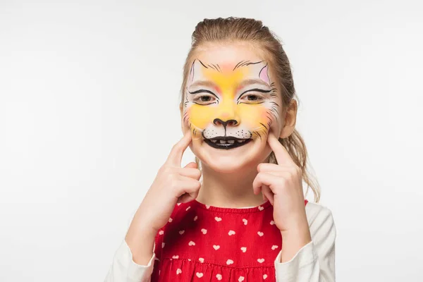 Cheerful child with tiger muzzle painting on face touching face with fingers isolated on white — Stock Photo