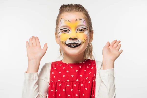 Allegro bambino con muso di tigre pittura sul viso guardando la fotocamera mentre in piedi con le braccia aperte isolato su bianco — Foto stock