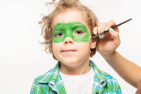 Partial view of artist painting gecko mask on face of adorable boy isolated on white — Stock Photo