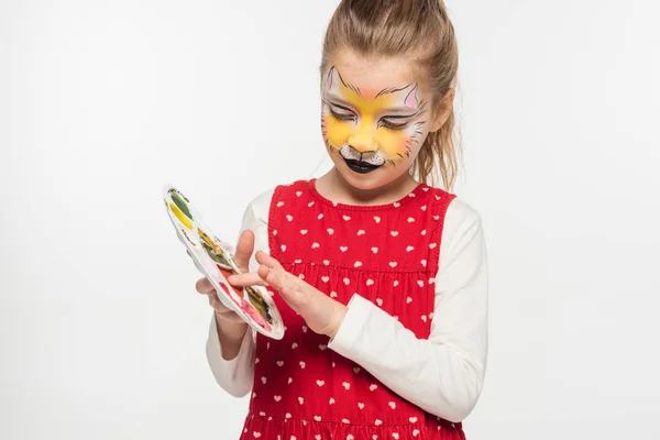 Adorabile bambino con muso di tigre pittura sul viso toccando tavolozza con dito isolato su bianco — Foto stock