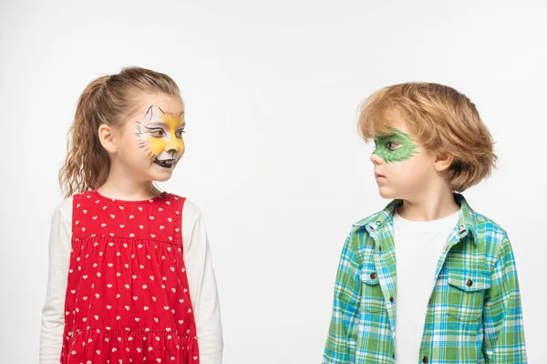 Mignons amis avec muselière de chat et peintures de masque de gecko sur les visages se regardant isolés sur blanc — Photo de stock