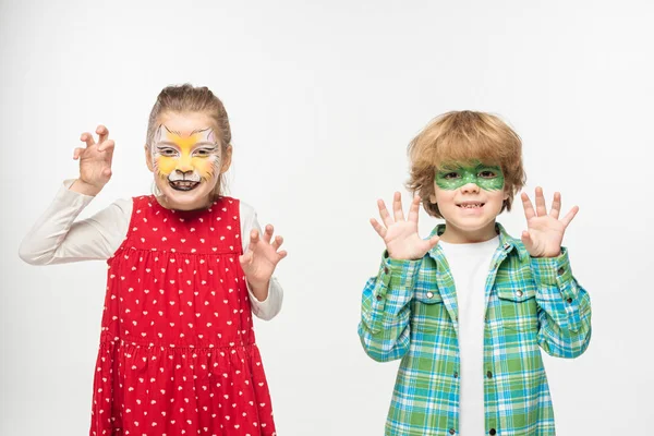 Cheerful friends with cat muzzle and gecko mask paintings on faces showing frightening gestures at camera isolated on white — Stock Photo