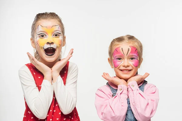 Excited friends with cat muzzle and butterfly paintings on faces looking at camera isolated on white — Stock Photo