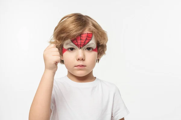 Lindo, niño seguro de sí mismo con máscara de superhéroe pintado en la cara que muestra el puño en la cámara aislado en blanco - foto de stock