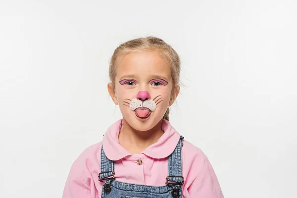 Fröhliches Kind mit Katzenmaulbemalung im Gesicht, das die Zunge herausstreckt, während es isoliert auf weiß in die Kamera schaut — Stockfoto