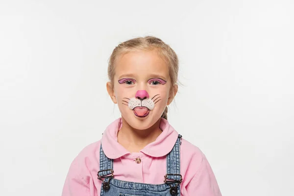 Niño alegre con la pintura del hocico del gato en la cara que sobresale lengua hacia fuera mientras que mira la cámara aislada en blanco - foto de stock