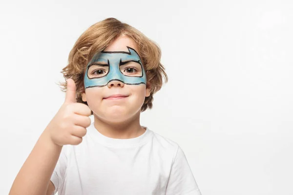 Fröhlicher Junge mit Superheldenmaske im Gesicht, der den Daumen nach oben zeigt, während er isoliert auf weiß in die Kamera schaut — Stockfoto