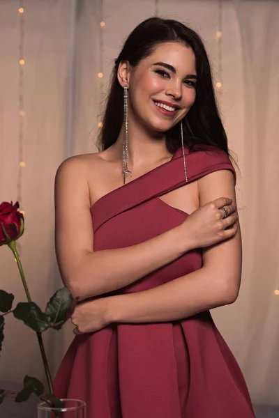 Hermosa, chica feliz en vestido elegante sonriendo a la cámara mientras está de pie en el restaurante - foto de stock