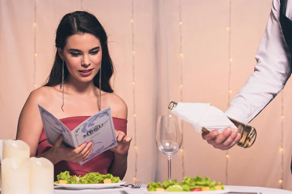 Atraente, elegante menu de leitura menina enquanto garçom derramando vinho branco em vidro — Fotografia de Stock