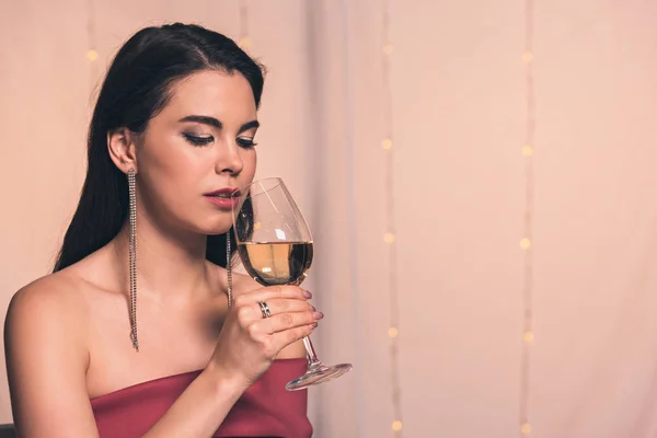 Beautiful, dreamy girl holding glass of white wine in restaurant — Stock Photo