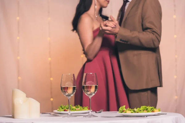 Cropped view of elegant man and woman dancing in restaurant near served table — Stock Photo