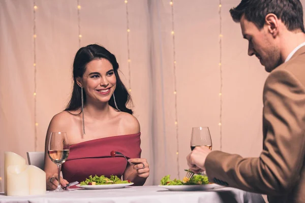 Heureuse, fille élégante et beau petit ami assis à la table servie au restaurant et tenant des verres de vin blanc — Photo de stock