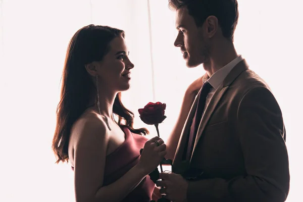 Vista laterale di bell'uomo che presenta rosa a fidanzata felice su San Valentino — Foto stock