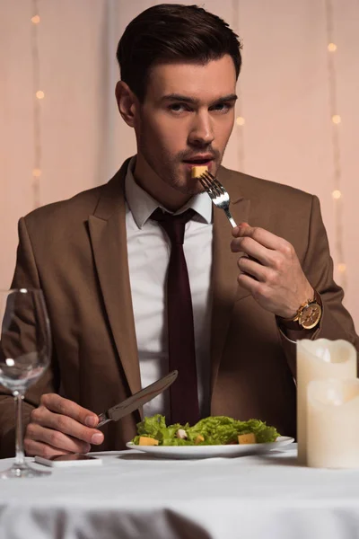 Schöner, eleganter Mann blickt in die Kamera, während er im Restaurant Salat isst — Stockfoto