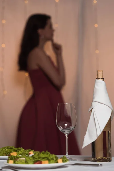 Enfoque selectivo de elegante, chica reflexiva de pie cerca de la mesa servida en el restaurante - foto de stock