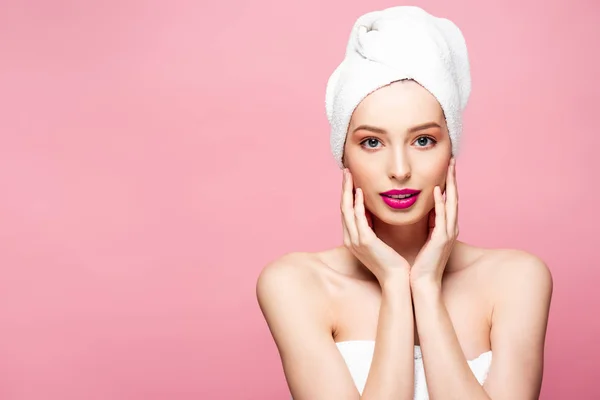 Beautiful young woman in white towel touching face isolated on pink — Stock Photo